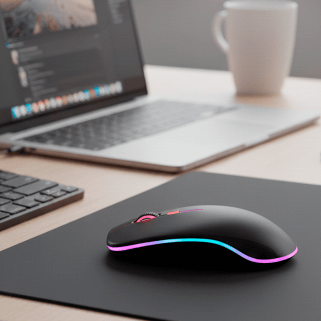 Mouse sem fio com LED RGB 2.4GHz em uso sobre mesa de trabalho ao lado de notebook